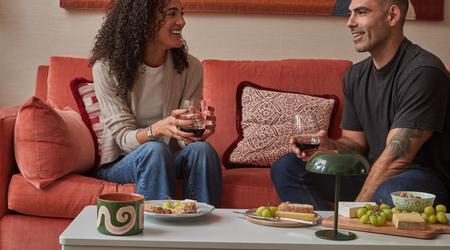 Man and woman sitting on couch anjoying wine and cheese and using the Fittle Box as a coffee table.