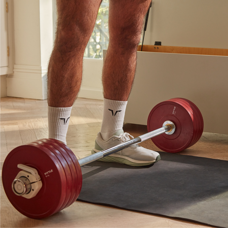 Fittle adjustable barbell with red Fittle weight plates in a modern home interior