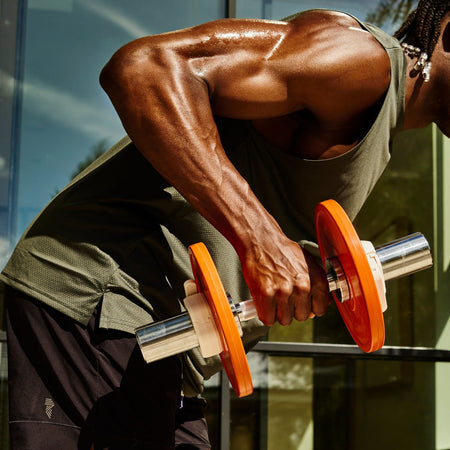 Man performing a single arm dumbbell row outdoors with a Fittle adjustable dumbbell, chrome bar and orange weight plates