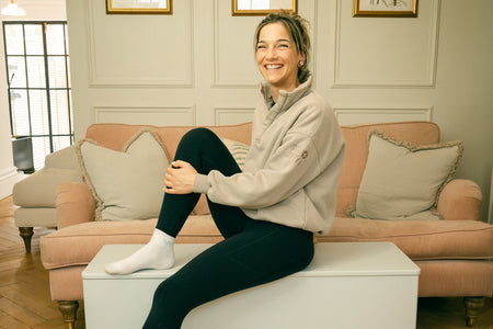 Woman smiling while sitting on the Fittle Box strength training bench in a UK living room home gym setup