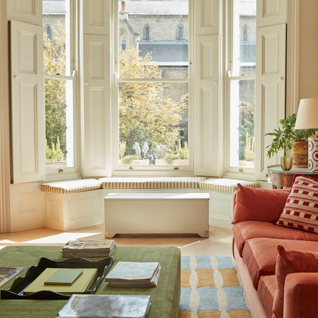 Bright modern living room with natural light and a soft grey closed Fittle Box under the window, blending stylish home décor with discreet strength training storage